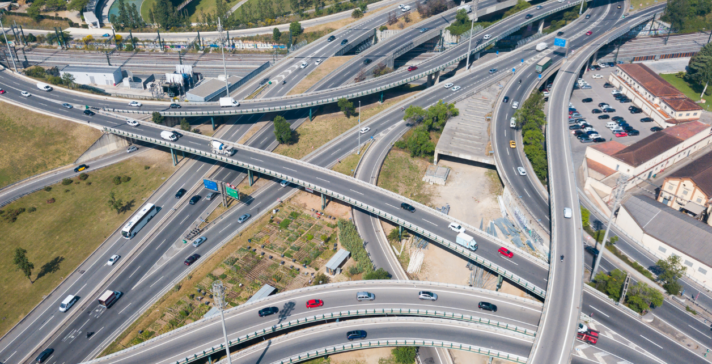 Aerial view of a complex multi-level highway interchange with overlapping overpasses, ramps, and traffic, representing large-scale transportation infrastructure