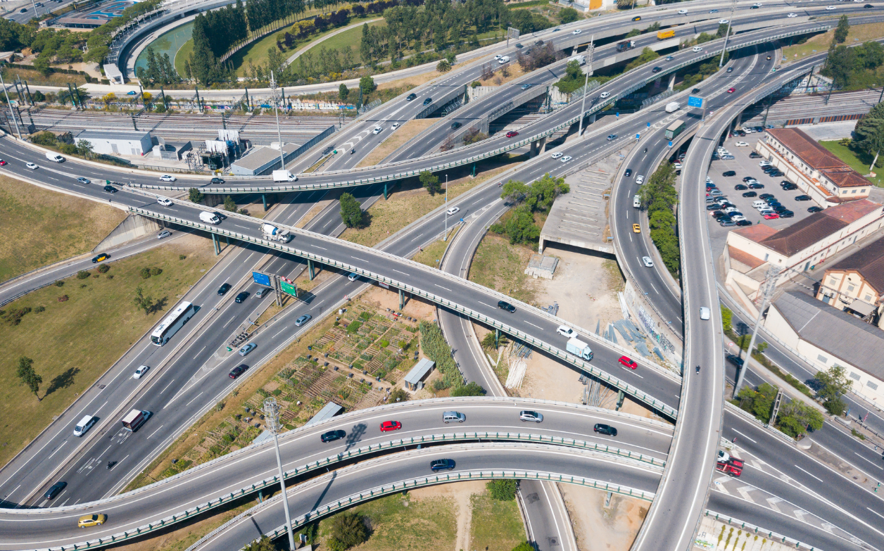 Aerial view of a complex multi-level highway interchange with overlapping overpasses, ramps, and traffic, representing large-scale transportation infrastructure