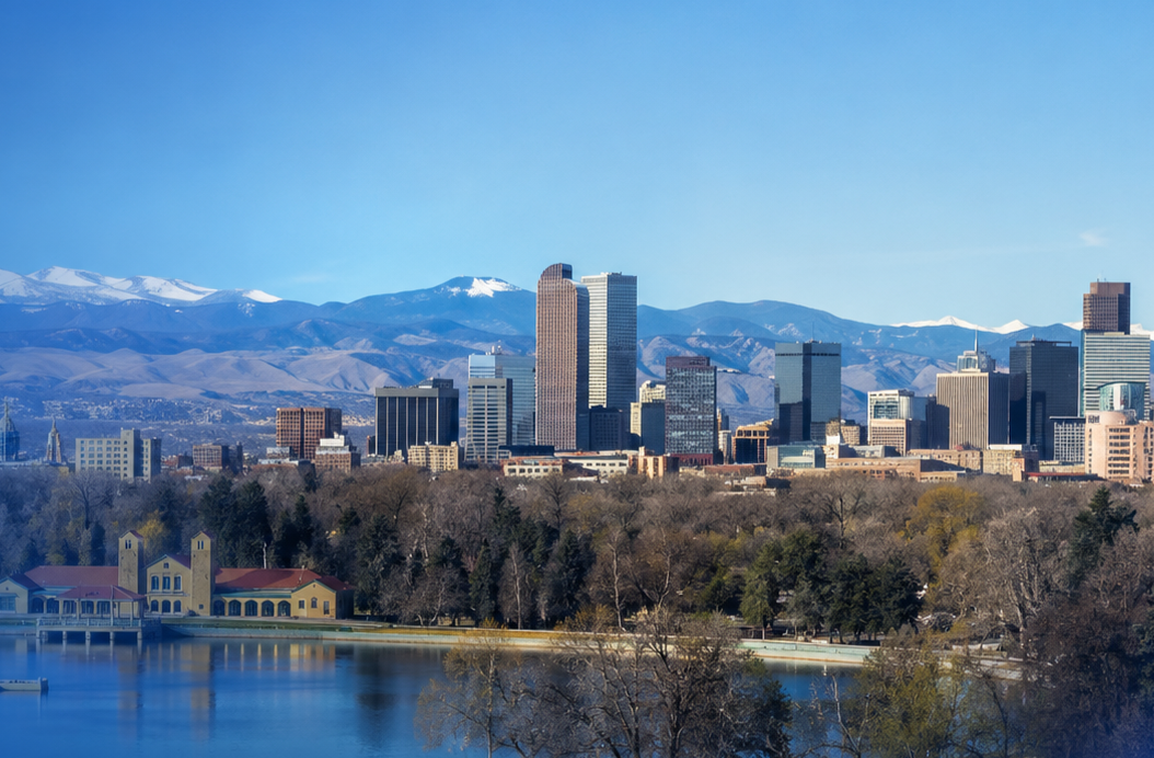 Wide view of the Denver skyline with mountains in the background, a lake and park in the foreground, and a blue brand-style overlay.