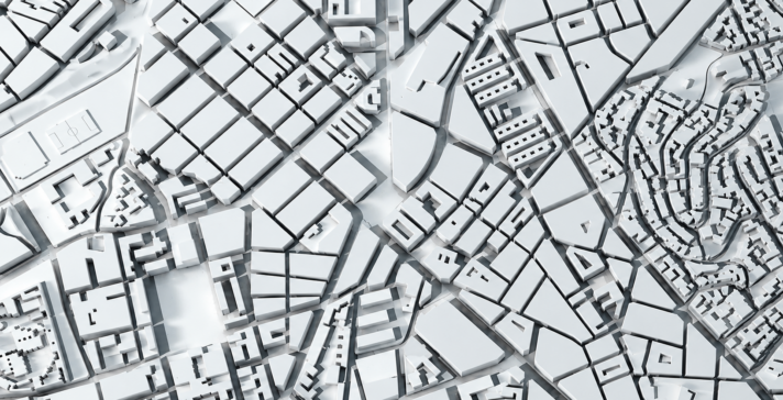Aerial view of a white 3D scale model of a city, showing blocks of buildings, streets, and varied urban density in monochrome