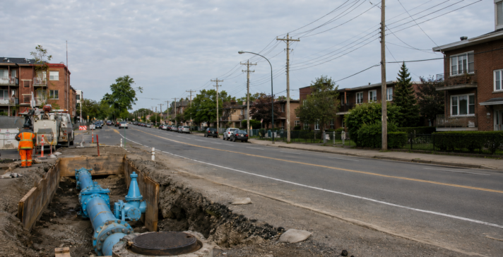 Open trench on a residential street showing a newly installed water main with valves and a hydrant connection
